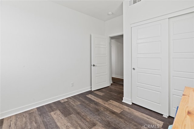 unfurnished bedroom featuring a closet and dark hardwood / wood-style flooring