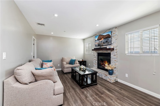 living room with dark hardwood / wood-style floors and a stone fireplace