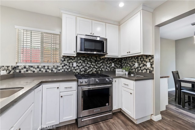 kitchen with decorative backsplash, white cabinetry, dark hardwood / wood-style flooring, stainless steel appliances, and sink