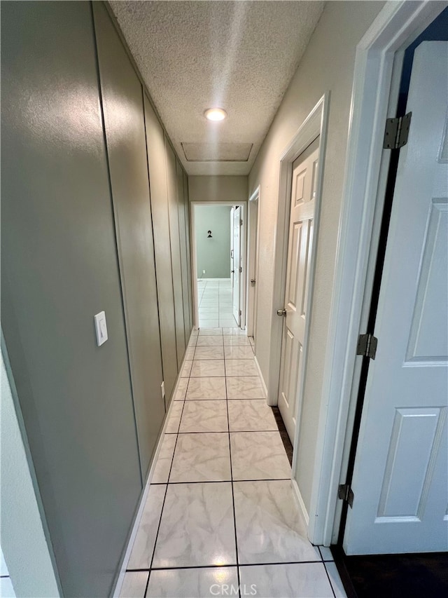 hallway featuring a textured ceiling and light tile patterned floors