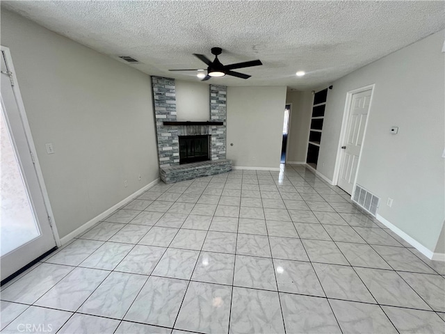 unfurnished living room with a textured ceiling, a fireplace, ceiling fan, and built in shelves