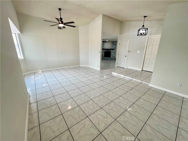 unfurnished living room with a textured ceiling, ceiling fan with notable chandelier, and light tile patterned floors