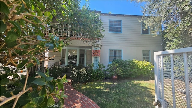 view of side of home with a balcony and a lawn