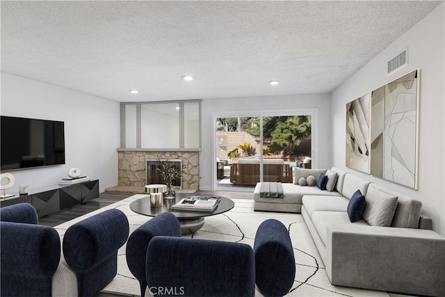 living room featuring a stone fireplace and a textured ceiling