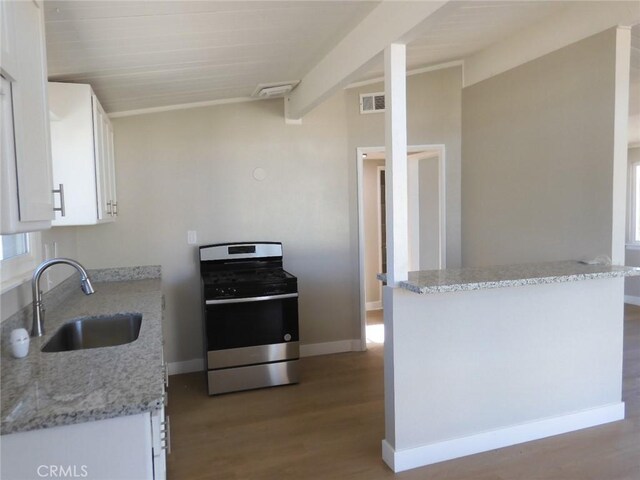 kitchen with light stone counters, white cabinets, hardwood / wood-style flooring, sink, and stainless steel range