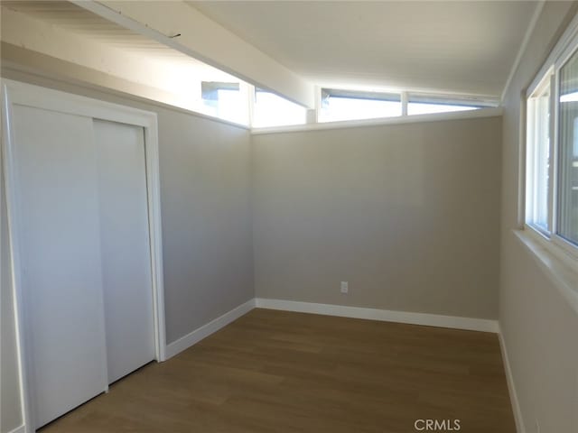 unfurnished room featuring vaulted ceiling with beams, hardwood / wood-style floors, and plenty of natural light