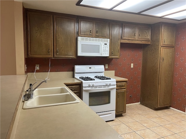 kitchen with white appliances, dark brown cabinetry, light tile patterned flooring, and sink