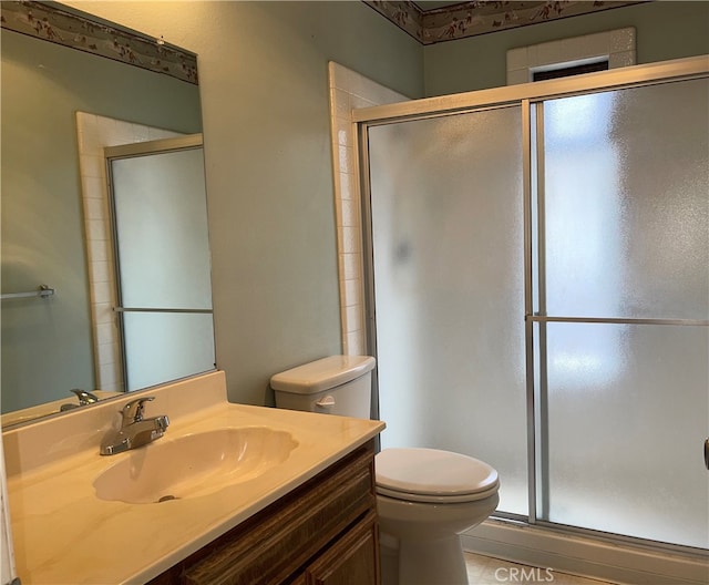 bathroom featuring tile patterned floors, a shower with door, vanity, and toilet