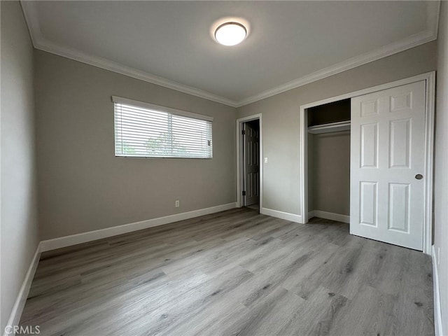 unfurnished bedroom featuring light hardwood / wood-style floors, ornamental molding, and a closet