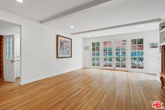 unfurnished living room featuring beam ceiling and light hardwood / wood-style flooring