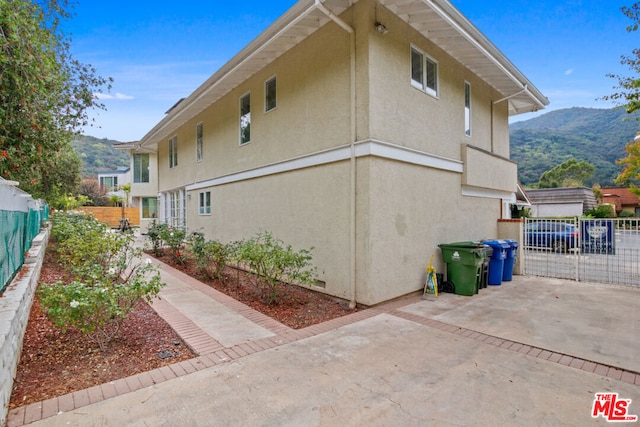 view of property exterior with a patio area and a mountain view