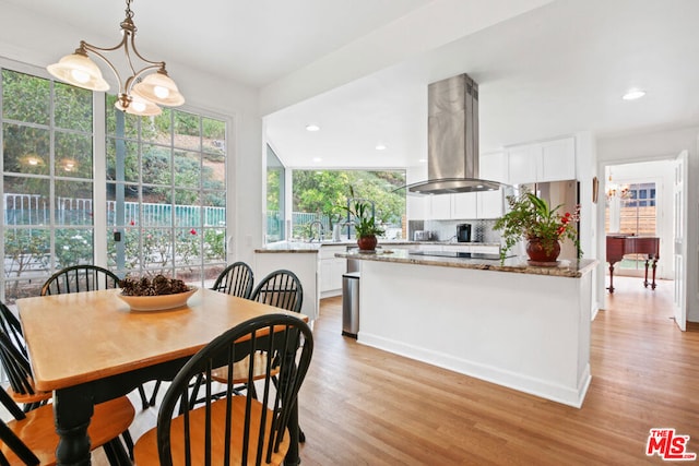 dining area with sink, light hardwood / wood-style floors, and an inviting chandelier