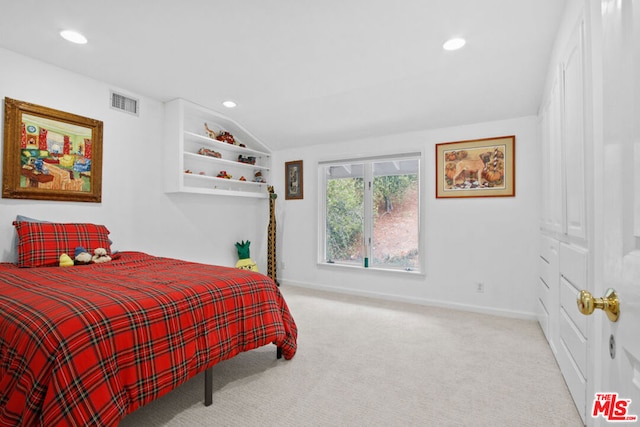 bedroom with light colored carpet and vaulted ceiling