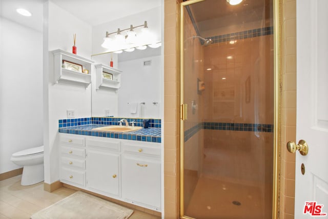 bathroom with tile patterned floors, vanity, toilet, and a shower with shower door