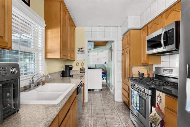 kitchen featuring appliances with stainless steel finishes, backsplash, sink, and light tile patterned floors