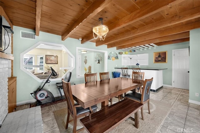 dining room featuring wooden ceiling, beam ceiling, and a brick fireplace