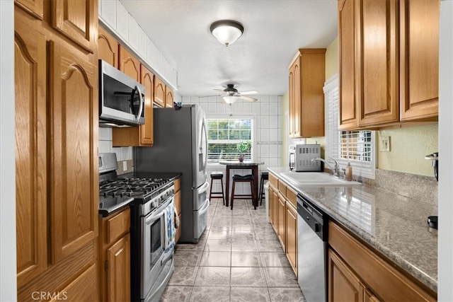 kitchen featuring ceiling fan, appliances with stainless steel finishes, sink, and decorative backsplash