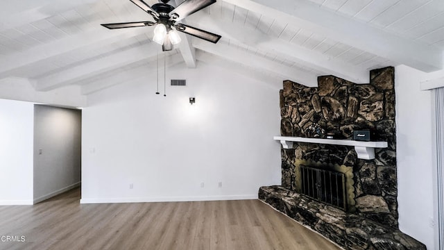 unfurnished living room with wood-type flooring, a stone fireplace, vaulted ceiling with beams, and ceiling fan