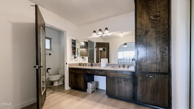 bathroom featuring a textured ceiling, hardwood / wood-style floors, vanity, and toilet