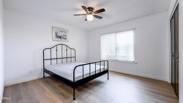 bedroom featuring ceiling fan, light hardwood / wood-style flooring, and a closet