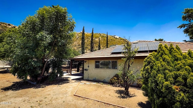 rear view of property with solar panels and a patio