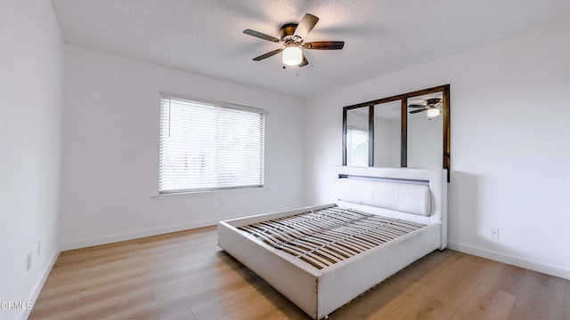 bedroom with ceiling fan, a textured ceiling, and light hardwood / wood-style flooring