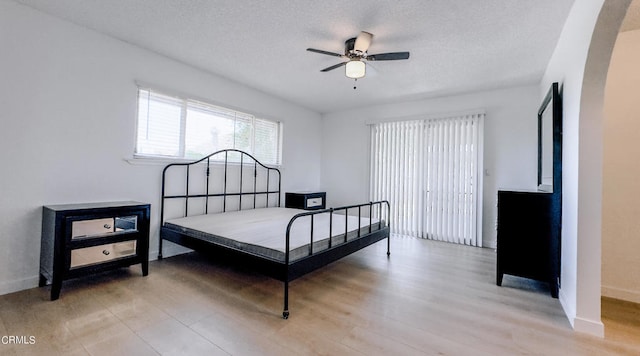 bedroom featuring ceiling fan, a textured ceiling, and light wood-type flooring