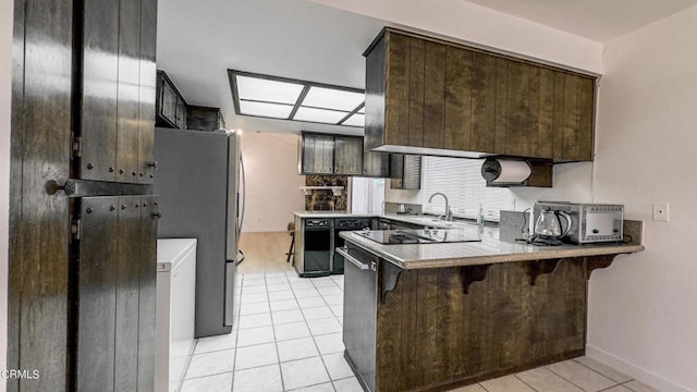 kitchen featuring dark brown cabinetry, light tile patterned floors, kitchen peninsula, stainless steel refrigerator, and a breakfast bar