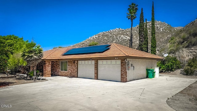 view of front of home with a mountain view, solar panels, and a garage