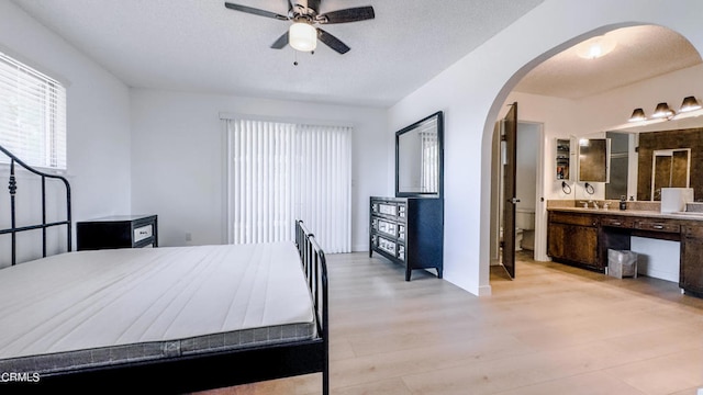 bedroom featuring ensuite bath, light hardwood / wood-style flooring, and ceiling fan