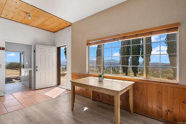 entryway featuring a mountain view, wood walls, independent washer and dryer, wooden ceiling, and light wood-type flooring