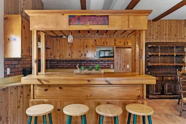 bar with wooden walls, beam ceiling, butcher block counters, and light tile patterned floors