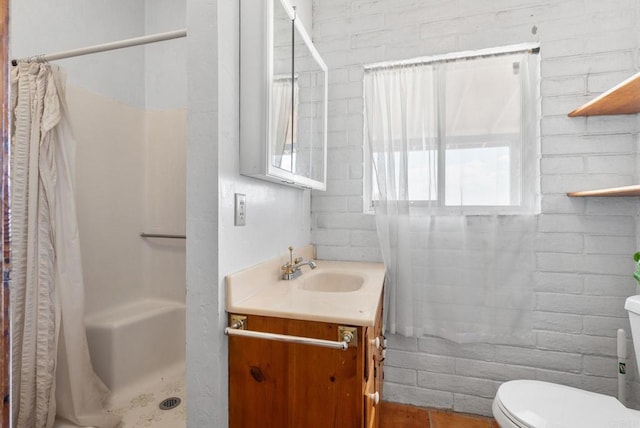 bathroom with vanity, toilet, a shower with shower curtain, and brick wall