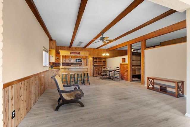 recreation room featuring light wood-type flooring, beam ceiling, wood walls, and ceiling fan