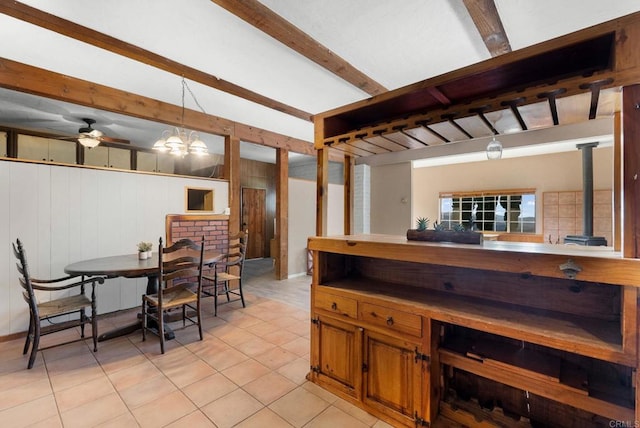 kitchen with ceiling fan, beamed ceiling, hanging light fixtures, a wood stove, and wooden walls