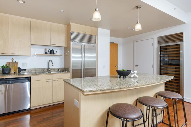 kitchen with pendant lighting, beverage cooler, stainless steel appliances, a center island, and dark hardwood / wood-style flooring