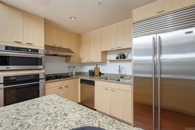 kitchen with appliances with stainless steel finishes, light stone countertops, sink, and light brown cabinets