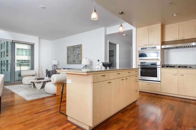 kitchen featuring hanging light fixtures, a kitchen island, dark wood-type flooring, stainless steel appliances, and a kitchen breakfast bar