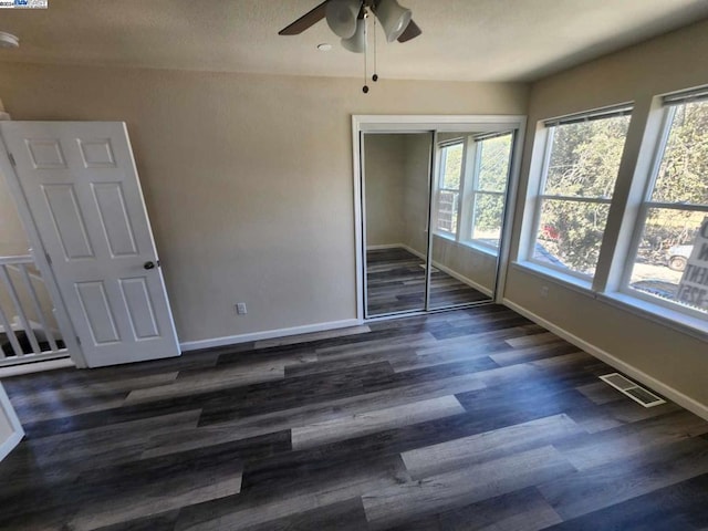 unfurnished bedroom featuring a closet, dark hardwood / wood-style floors, and ceiling fan