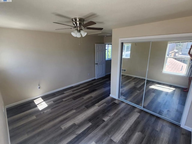 unfurnished bedroom with dark hardwood / wood-style flooring, ceiling fan, and a closet