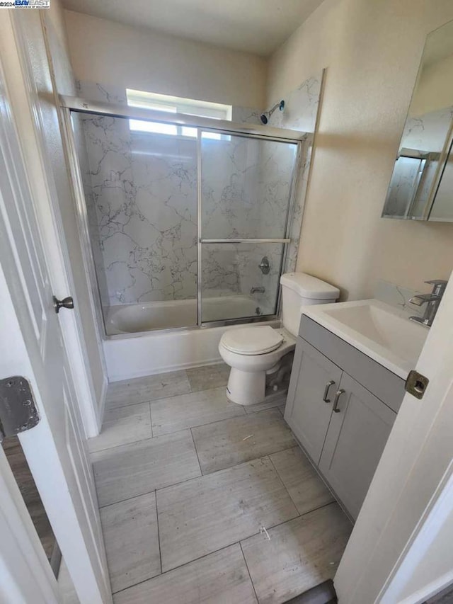 full bathroom with shower / bath combination with glass door, vanity, and toilet