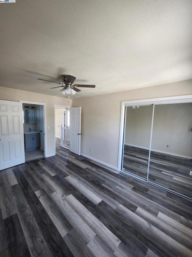 unfurnished bedroom featuring ceiling fan, a textured ceiling, a closet, and dark wood-type flooring