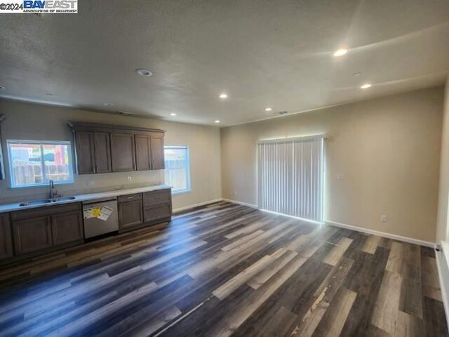 kitchen with dark brown cabinetry, sink, dark wood-type flooring, and stainless steel dishwasher