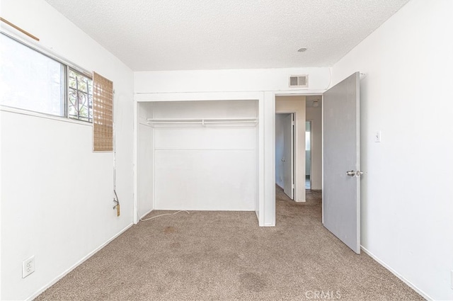 unfurnished bedroom with light carpet, a closet, and a textured ceiling