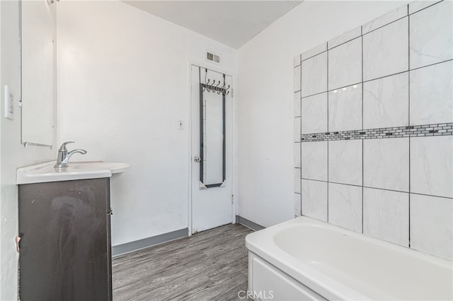 bathroom featuring vanity, hardwood / wood-style flooring, and a bathtub