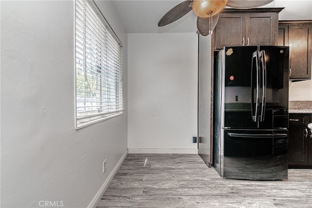 kitchen with dark brown cabinetry, light hardwood / wood-style flooring, black refrigerator, and ceiling fan