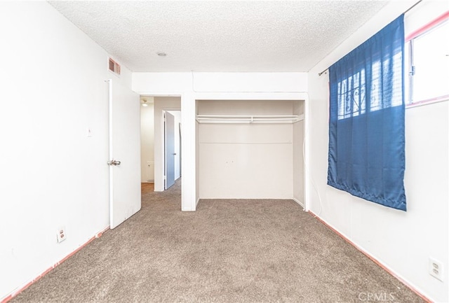 unfurnished bedroom featuring a textured ceiling, carpet, and a closet