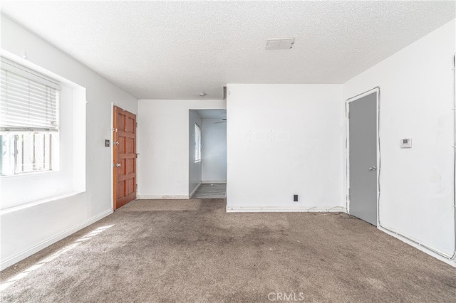 unfurnished room featuring a textured ceiling and carpet