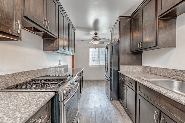 kitchen featuring ceiling fan, dark brown cabinets, refrigerator, light wood-type flooring, and stainless steel range with gas cooktop