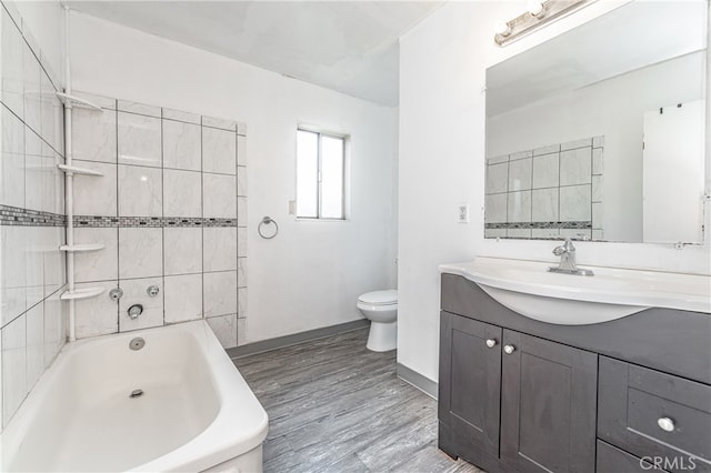 bathroom featuring vanity, wood-type flooring, a tub, and toilet